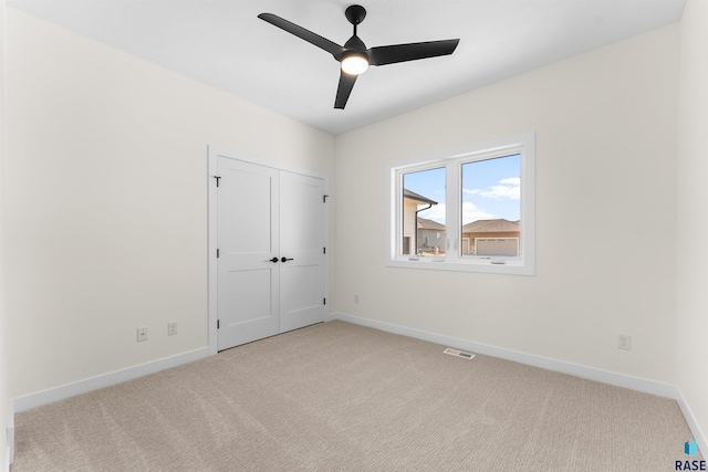 unfurnished bedroom featuring visible vents, a ceiling fan, a closet, baseboards, and light colored carpet