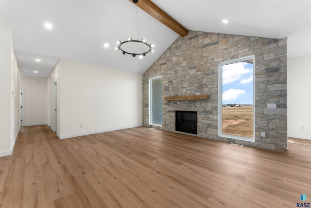 unfurnished living room featuring light wood-type flooring, beam ceiling, high vaulted ceiling, a stone fireplace, and baseboards