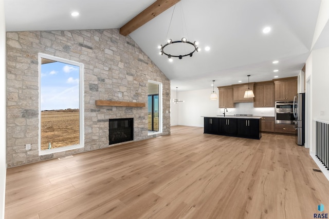 kitchen featuring a stone fireplace, light wood-style floors, open floor plan, and appliances with stainless steel finishes