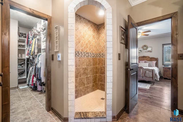 ensuite bathroom with connected bathroom, tiled shower, baseboards, and ornamental molding