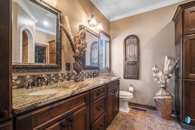 full bath with baseboards, toilet, double vanity, ornamental molding, and a sink