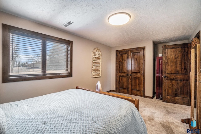 bedroom with a closet, visible vents, a textured ceiling, and carpet