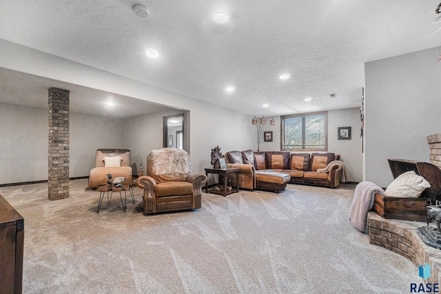 carpeted living room with recessed lighting, a textured ceiling, and ornate columns