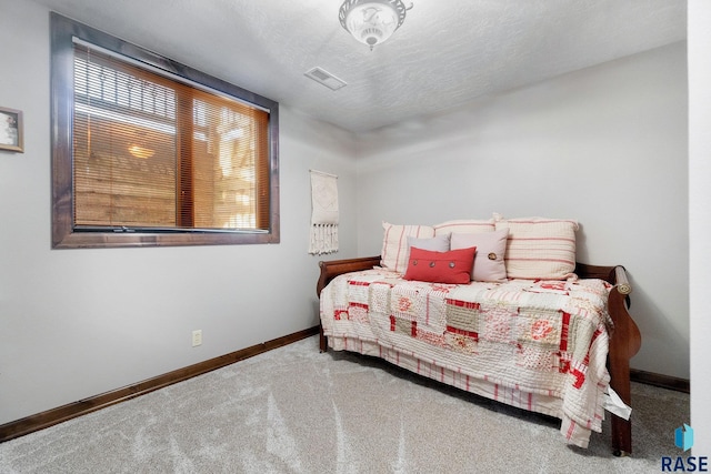 bedroom with visible vents, multiple windows, a textured ceiling, and carpet flooring