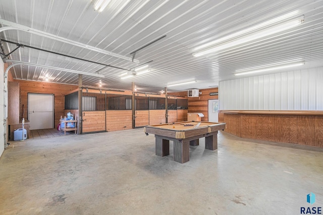 playroom with a garage, concrete floors, an AC wall unit, and metal wall