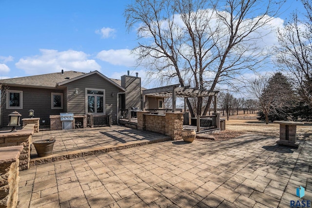 view of patio featuring area for grilling, exterior kitchen, and a pergola