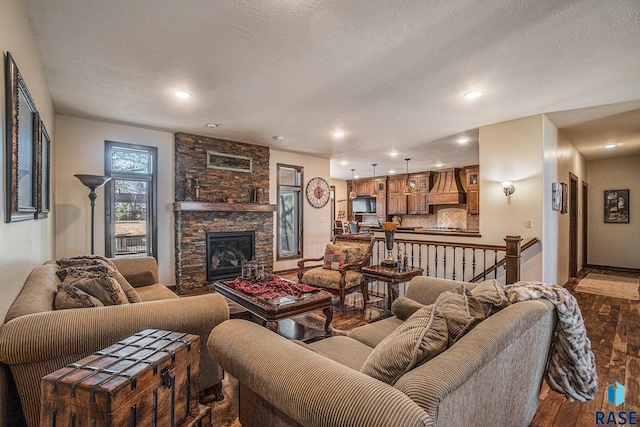 living area with a textured ceiling, wood finished floors, recessed lighting, a fireplace, and baseboards