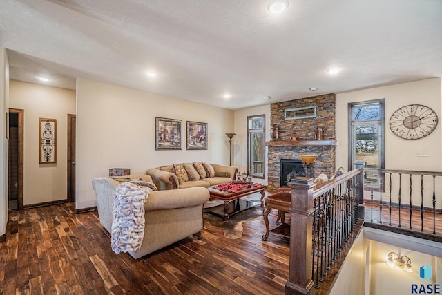 living room featuring a stone fireplace, dark wood-type flooring, and a healthy amount of sunlight