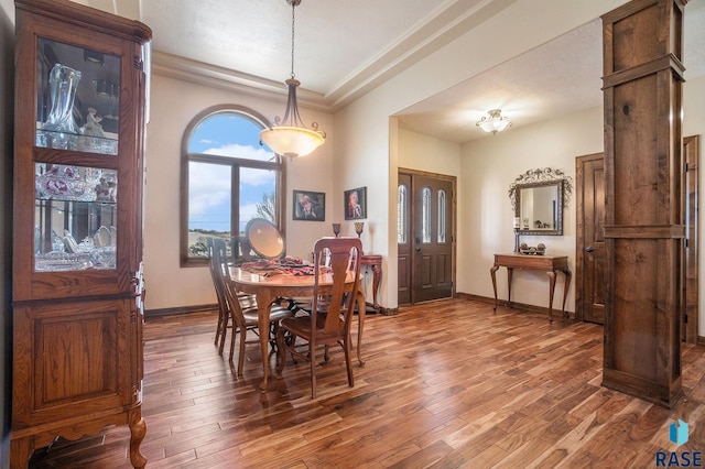 dining room with a raised ceiling, wood finished floors, and baseboards