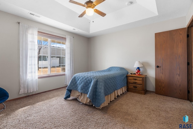 bedroom with visible vents, baseboards, a tray ceiling, and carpet floors