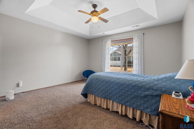 bedroom with visible vents, a raised ceiling, baseboards, and carpet flooring