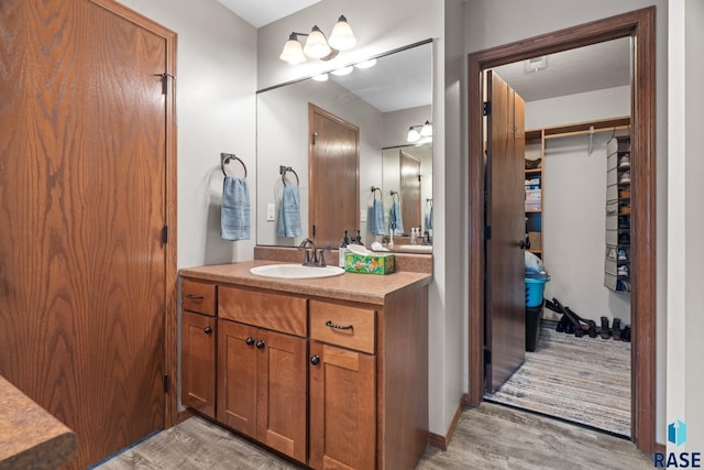 bathroom with vanity, a spacious closet, and wood finished floors