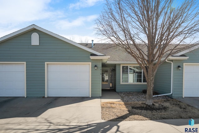 single story home with an attached garage, driveway, and roof with shingles