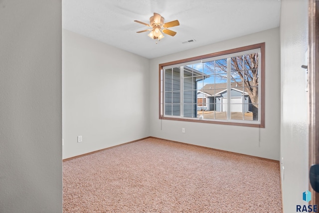 carpeted empty room with visible vents, baseboards, and ceiling fan