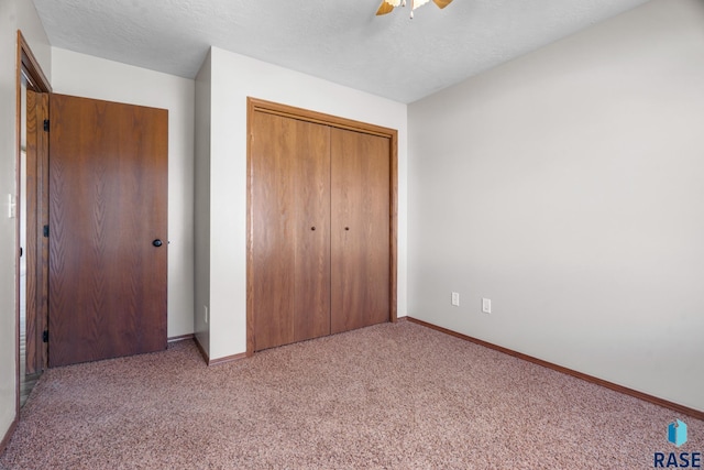 unfurnished bedroom with a ceiling fan, a textured ceiling, a closet, carpet, and baseboards