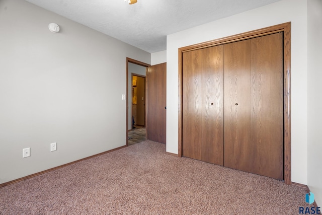 unfurnished bedroom with a closet, baseboards, a textured ceiling, and carpet flooring