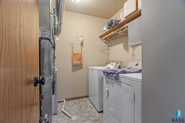 clothes washing area featuring washer and dryer, laundry area, baseboards, and a textured ceiling