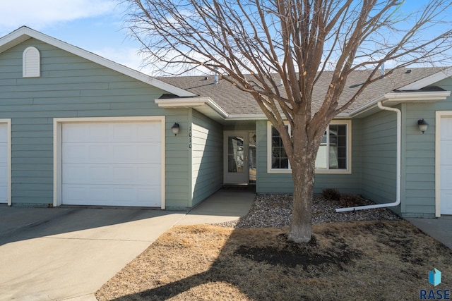 single story home featuring concrete driveway, a garage, and a shingled roof