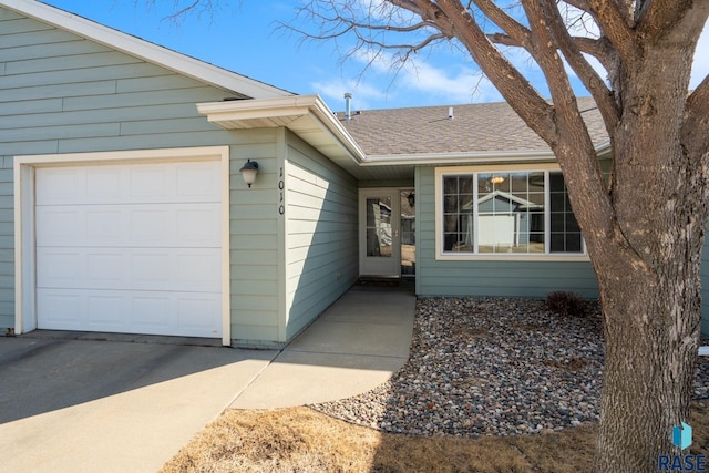 entrance to property with roof with shingles and an attached garage