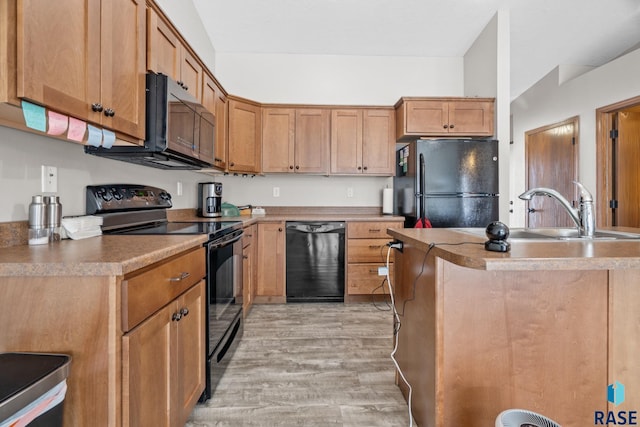 kitchen featuring a sink, black appliances, and light wood finished floors