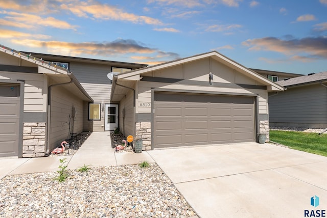 view of front of property featuring concrete driveway, a garage, and stone siding