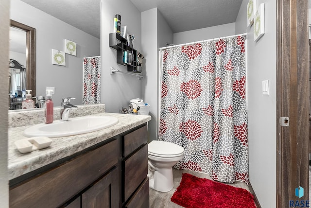 full bath with vanity, wood finished floors, a textured ceiling, curtained shower, and toilet