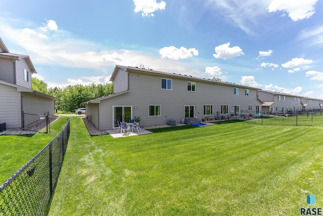 rear view of house with a fenced backyard, a patio, and a yard