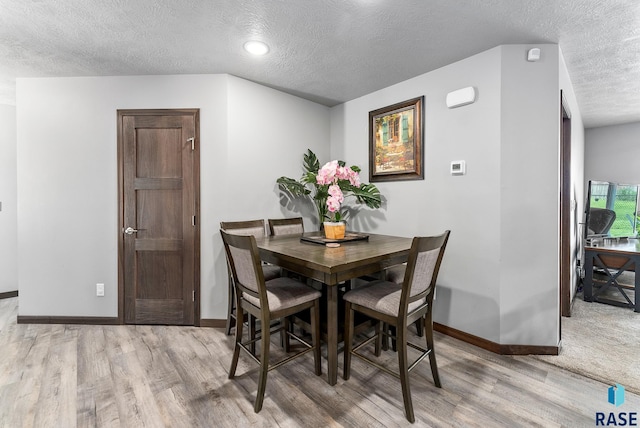 dining room featuring a textured ceiling, baseboards, and wood finished floors