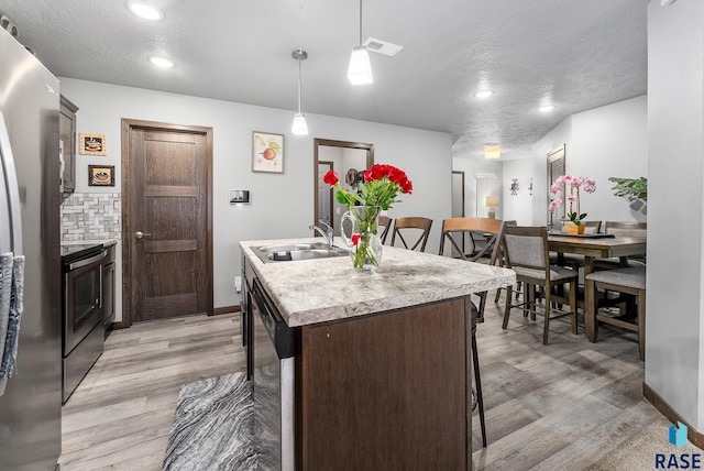 kitchen with visible vents, stainless steel appliances, light wood finished floors, and a sink