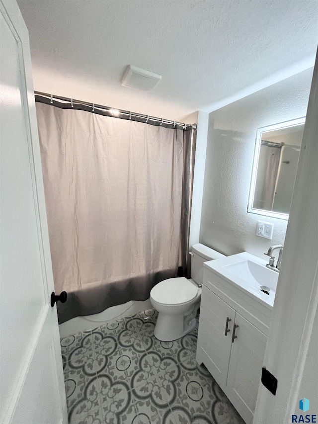 bathroom with shower / bath combo with shower curtain, toilet, vanity, a textured wall, and a textured ceiling