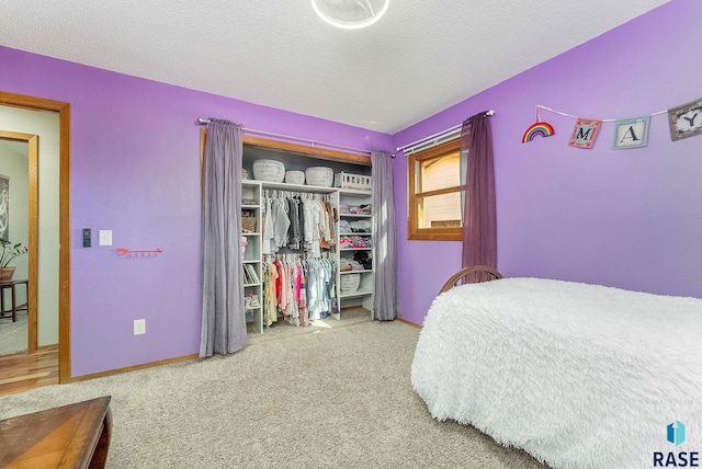 carpeted bedroom featuring baseboards, a closet, and a textured ceiling