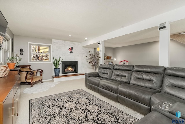 carpeted living area with baseboards, a large fireplace, and a textured ceiling