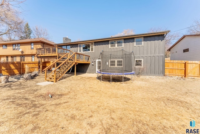 back of house featuring stairs, a trampoline, fence, and a wooden deck