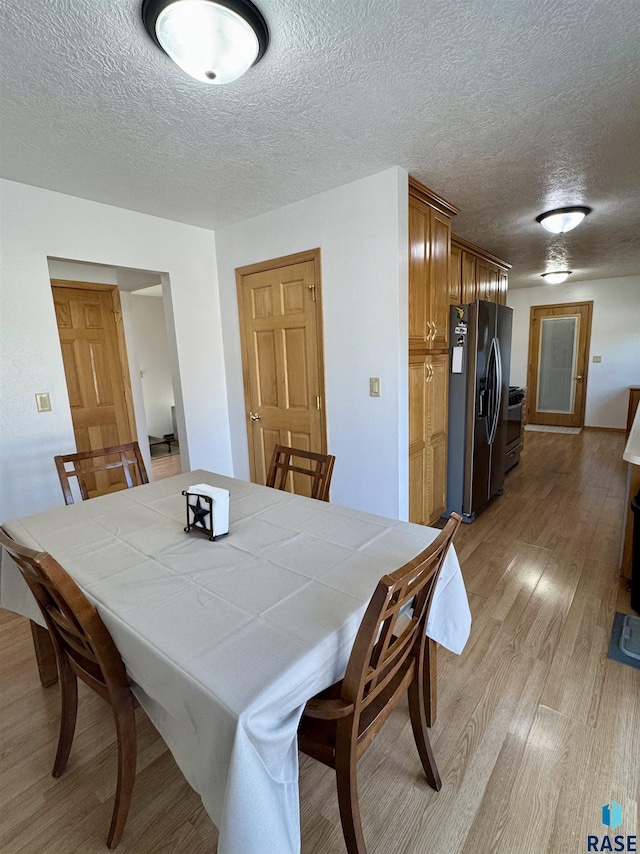 dining area with light wood-type flooring and a textured ceiling