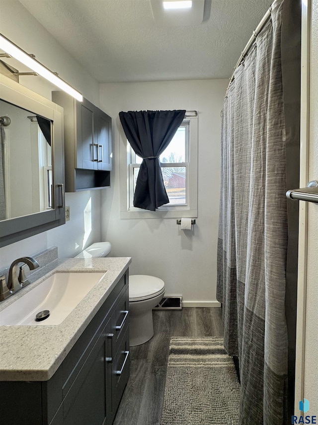 full bath featuring visible vents, toilet, a textured ceiling, wood finished floors, and vanity