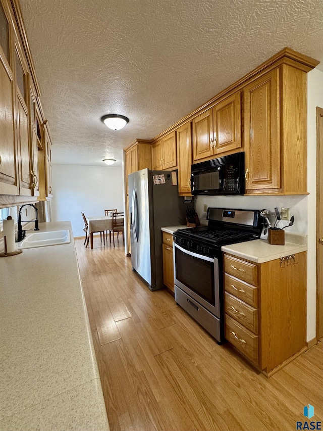 kitchen featuring a sink, brown cabinets, light wood finished floors, and stainless steel appliances