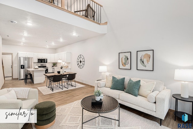 living area with light wood finished floors, a high ceiling, and baseboards