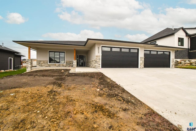 view of front of house featuring stone siding, driveway, and an attached garage