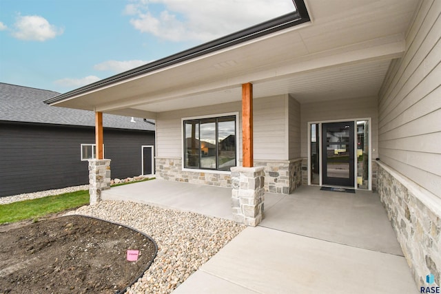 doorway to property featuring stone siding and a porch