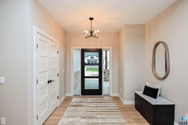 entrance foyer featuring a chandelier, light wood finished floors, and baseboards