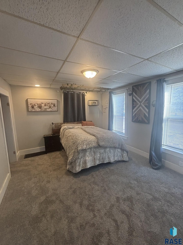 carpeted bedroom with a drop ceiling and baseboards