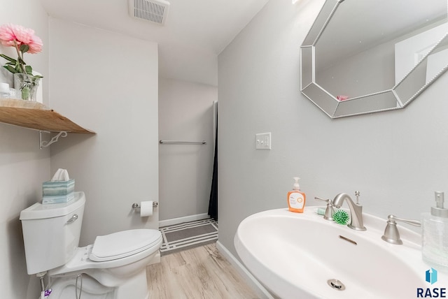 bathroom featuring wood finished floors, baseboards, visible vents, a sink, and toilet