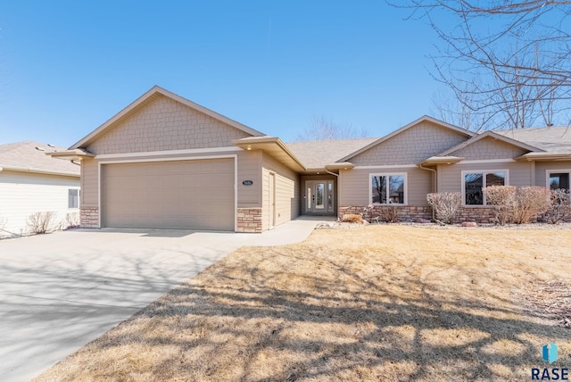 view of front facade featuring driveway, a garage, and stone siding