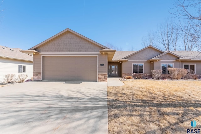 view of front facade featuring an attached garage, stone siding, and driveway