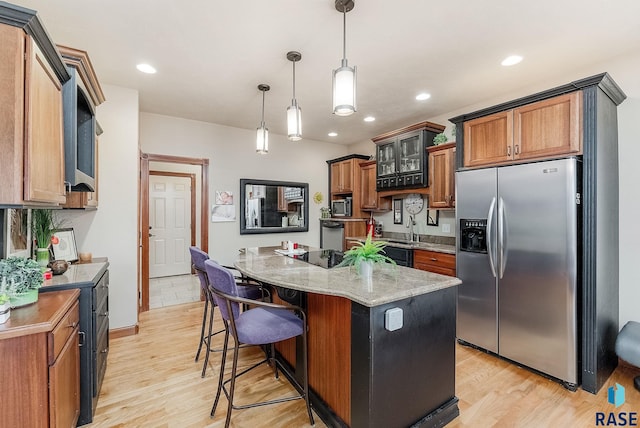 kitchen featuring light wood finished floors, appliances with stainless steel finishes, a center island, and light stone counters