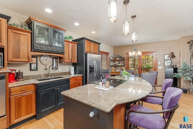 kitchen with a sink, stainless steel appliances, a kitchen island, and light wood-style flooring