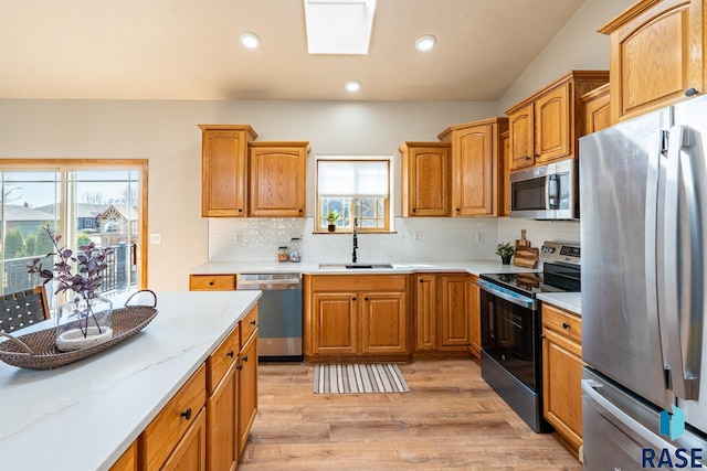 kitchen with backsplash, recessed lighting, light wood-style floors, stainless steel appliances, and a sink