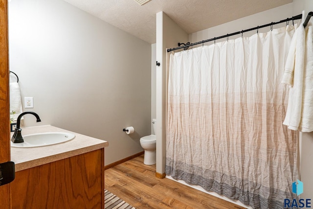 bathroom featuring vanity, a shower with curtain, wood finished floors, a textured ceiling, and toilet