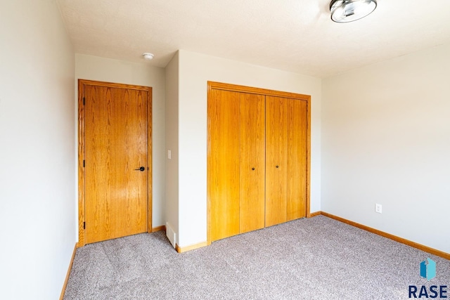 unfurnished bedroom featuring a closet, light carpet, and baseboards