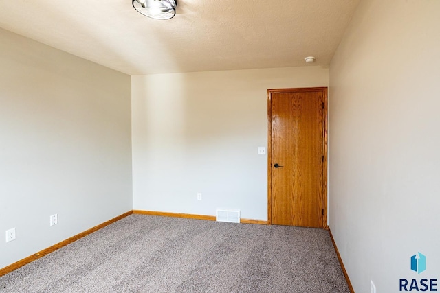 carpeted empty room featuring baseboards, visible vents, and a textured ceiling